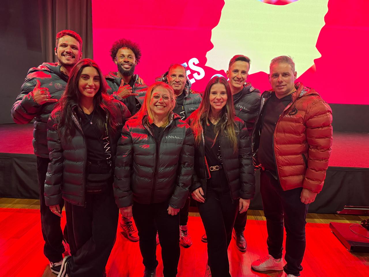 Equipe UNNA Live Marketing reunida em evento, vestindo jaquetas da marca.